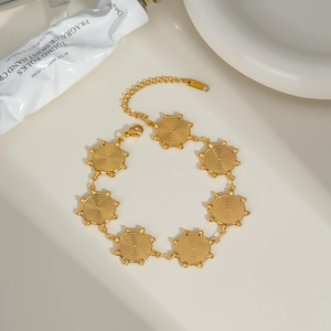 Detail of gold stainless steel bracelet with spiral sunburst discs and lobster clasp