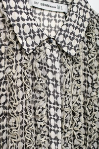 Detailed close-up of chiffon shirt featuring black abstract print and gold stripes with ruffles