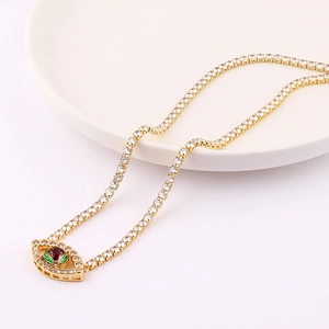 Macro shot of gold tennis chain necklace with colorful evil eye pendant on white ceramic