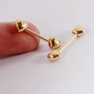 Vue macro détaillée montrant la taille de deux barbells dorés en forme de cœur sur fond blanc