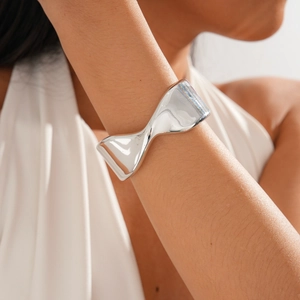 Detail of silver bow knot open bangle with high-polished metal finish on wrist