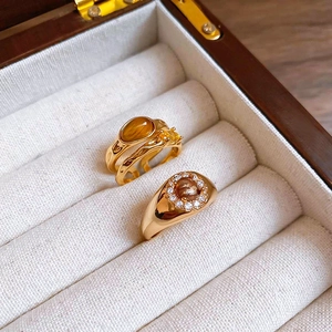 Detailed view of gold plated tiger eye stone and zircon rings in a beige velvet jewelry box