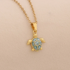 Detailed close-up of a golden sea turtle pendant necklace with green enamel shell finish