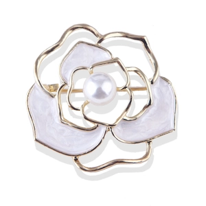 Golden camellia flower brooch with white enamel petals and pearl center on white background