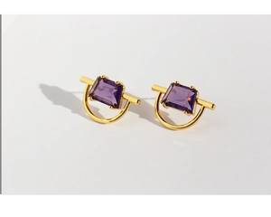 Detailed macro view of geometric earrings with purple zircon and 18k gold plating