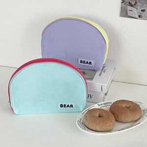 Close-up of mesh semicircular cosmetic bags with contrast zippers and Bear patch