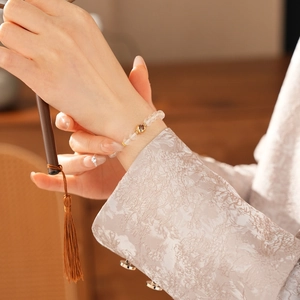 Close-up of white crystal bead bracelet with a gold hollow ball on a woman's wrist