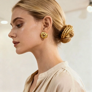 Close-up of elegant gold woven vortex flower earring worn on the ear for detail