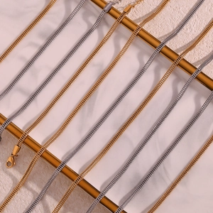 Close-up of 18K gold and silver foxtail chains with lobster clasps on marble background