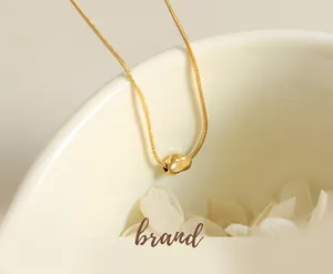Vista macro di una collana a catena a serpente placcata in oro 18k su ceramica bianca