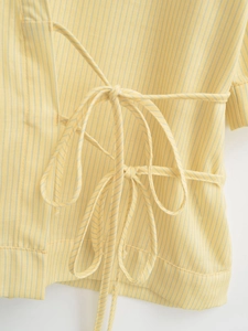 Close-up of yellow pinstripe blouse featuring elegant side-tie bow detail and soft fabric