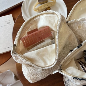 Detailed macro view of beige lace cosmetic bag with intricate crochet embroidery and zipper