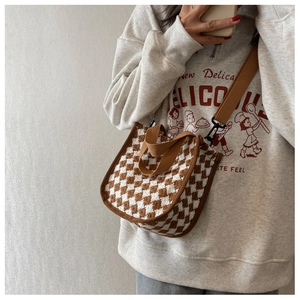 Macro detail of brown houndstooth woven fabric and sturdy strap on a crossbody bag