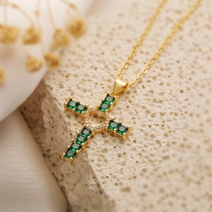 Macro shot of gold-plated cross pendant with emerald stones and heart-shaped center