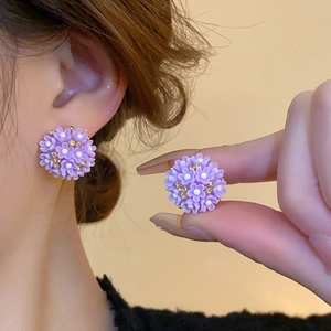 Détail de boucles d'oreilles fleurs en acrylique violet avec centres dorés