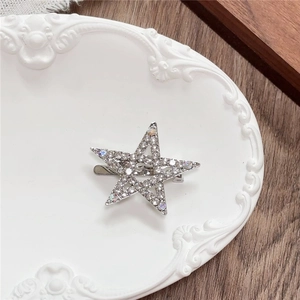 Detailed close-up of a silver star hair clip with rhinestones on a vintage plate