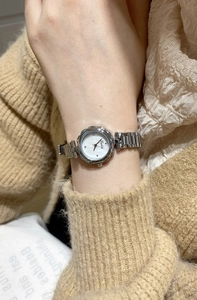Macro shot of silver floral steel band watch with white mother of pearl dial for women