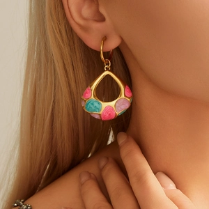 Close-up of golden water drop earrings with pastel enamel inlay worn by a model