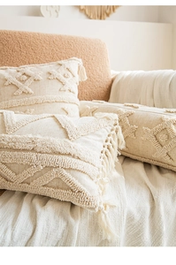 Detailed view of beige boho throw pillows with geometric tufting and tassel accents
