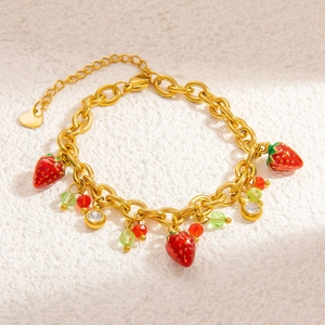 Detail of a golden stainless steel bracelet featuring red strawberry charms and clear beads