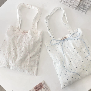Detail of canvas tote bags with heart prints, ribbon bow closure, and woven label
