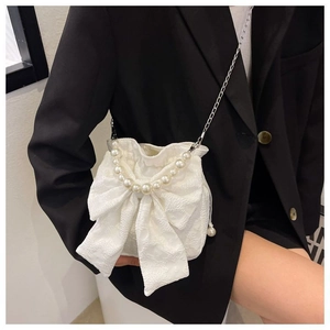Detail of white lace bow bucket bag with pearl handle worn with black blazer
