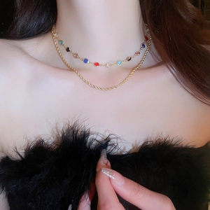 Detail of layered gold necklace with colorful zircon stones and twisted rope chain design