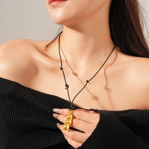 Détail du collier pendentif cacahuète doré avec cordon noir porté par un modèle