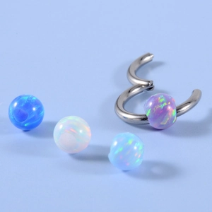 Macro detail of stainless steel piercing rings with four colorful opal stone beads