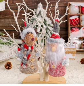 Close-up of knitted reindeer and gnome ornaments hanging on white branches for Christmas decor