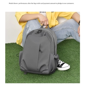 Grey minimalist campus backpack for students shown in a natural outdoor park setting