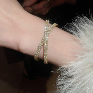 Gros plan d'un bracelet croisé doré de luxe avec diamants pavés sur un poignet