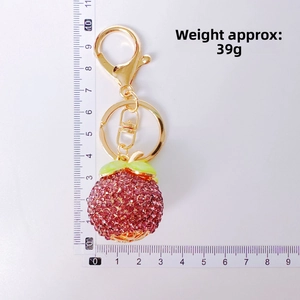 Detailed top view of rhinestone strawberry keychain with gold lobster clasp and scale ruler