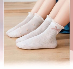 Détail de chaussettes bébé en maille blanche avec bordure en dentelle et noeud rose