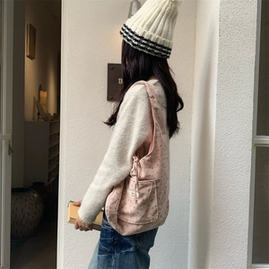 Detailed side view of pink corduroy tote bag with heart patterns and functional side pocket