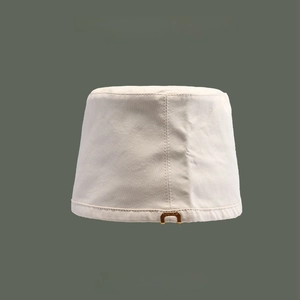Detail of a beige canvas bucket hat with high-quality stitching on a dark green background
