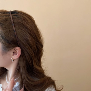 Elegant side view of a model wearing cluster pearl earrings and a leopard print headband