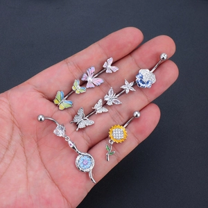 Collection of zircon belly button rings with butterfly and floral designs in hand