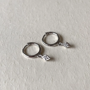 Macro detail of silver geometric rhombus earrings with sparkling white cubic zirconia