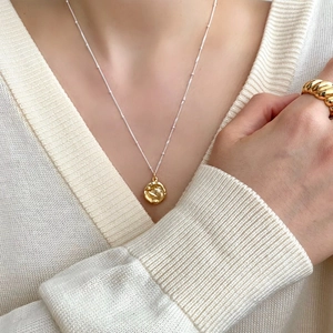 Detail of a gold irregular lava pendant necklace paired with a gold croissant dome ring