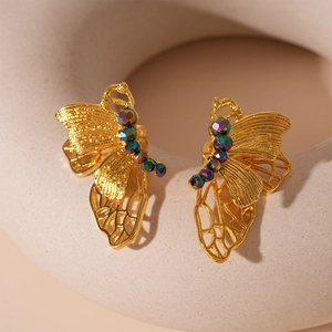 Macro detail of golden butterfly earring with hollow wings and iridescent beads