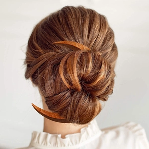 Detailed view of brown wooden crescent moon hair forks styled in a woman's hair bun