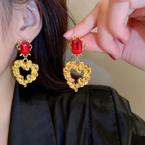 Detail of vintage palace style earrings with red rectangular gem and hollow heart pendant