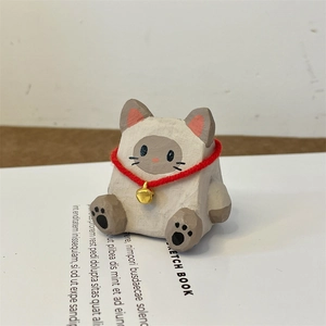 Détail d'une figurine de chat en bois peint à la main avec collier rouge et clochette