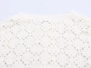 Detailed macro view of white crochet hollow-out knit fabric with delicate geometric patterns