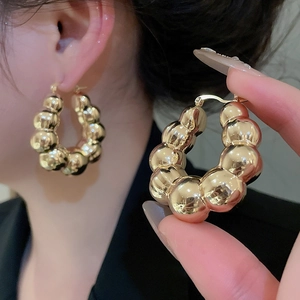 Macro shot of large polished gold sphere hoop earrings showing detailed craftsmanship