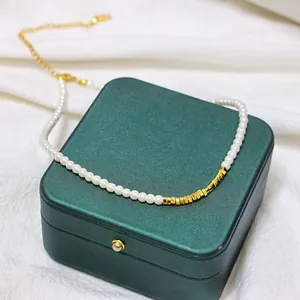 Detail of 14K gold plated pearl necklace with square beads on a green jewelry box