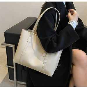Chic cream leather tote bag shown on a model with a minimalist black coat for winter style