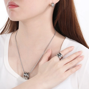 Elegant silver stainless steel jewelry set including necklace, ring, and earrings on model