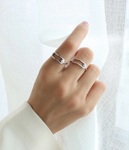 Detail showing minimalist gold-plated geometric ring with a white pearl on finger